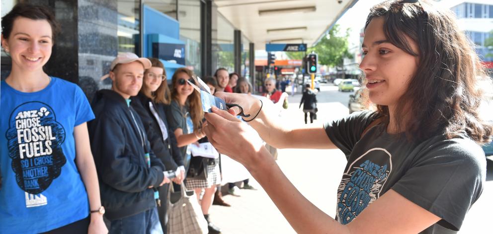 Claudia Palmer (20) cuts her ANZ eftpos card in half to protest against the bank’s investments in...