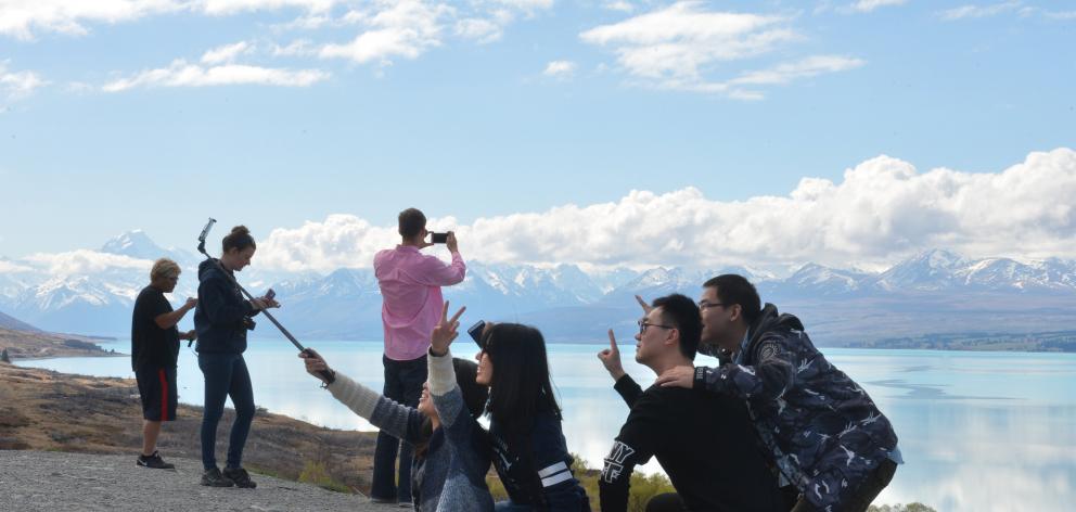 Some of the nearly 3.5 million visitors to New Zealand last year take selfies and photographs on the shores of Lake Pukaki. Photo by Stephen Jaquiery.