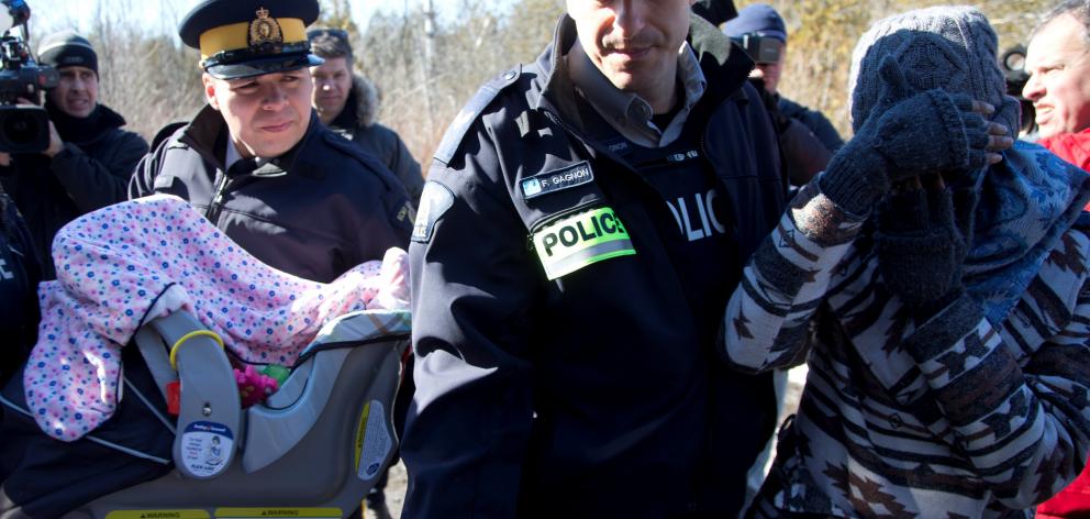 A mother and child are taken into custody by Royal Canadian Mounted Police after crossing the US...