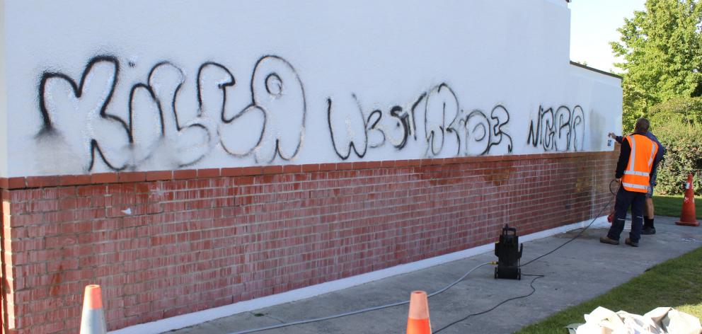 Volunteers clean graffiti from a wall at St Gerard’s School in Alexandra on Thursday  after a...