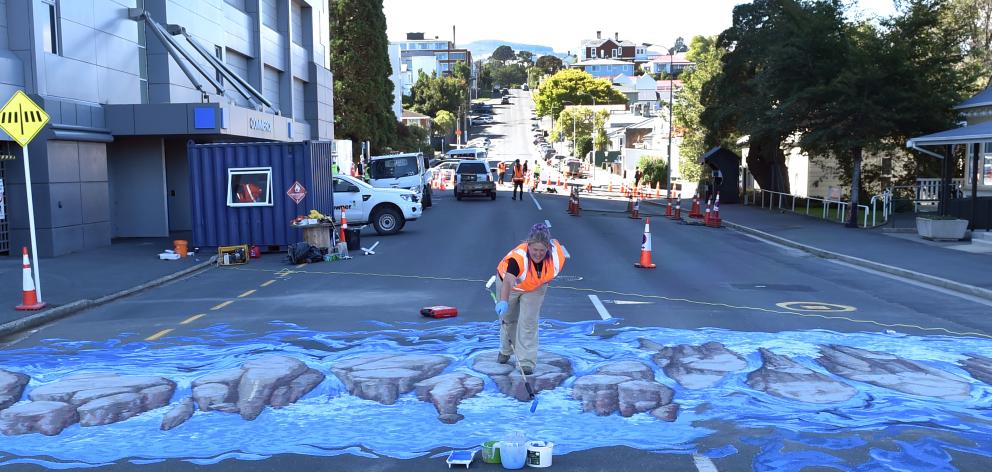 Artist Jenny McCracken works on the new 3-D pedestrian crossing with Downer contractor Nathan...