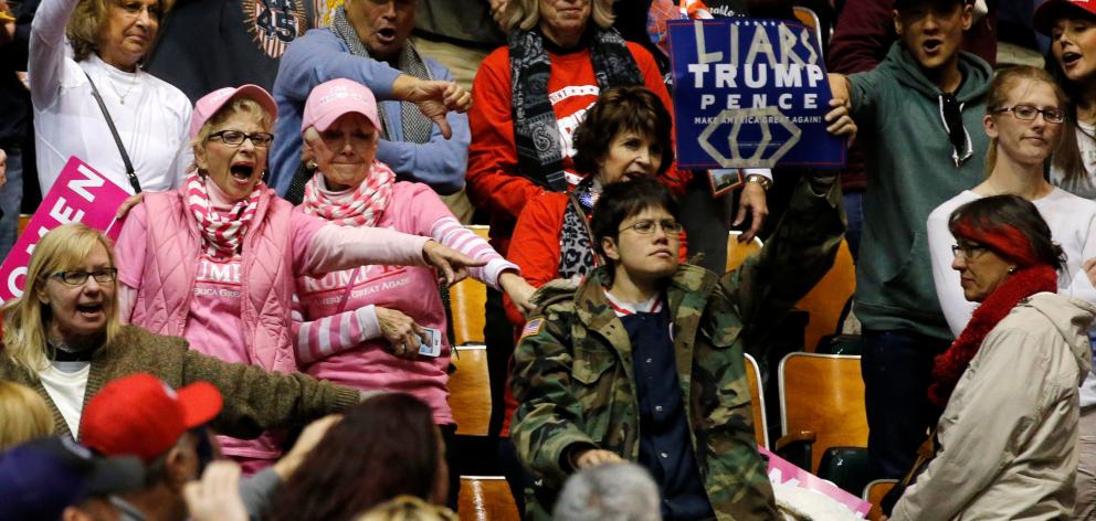 Supporters of US President Donald Trump jeer a protester who disrupted his rally at Municipal...