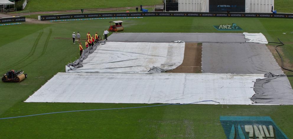 Ground staff supervised by reserve umpire Chris Brown (top) adjust the covers as rain delays the start of day five of the Test match between New Zealand and South Africa at Seddon Park on March 29, 2017 in Hamilton :Getty