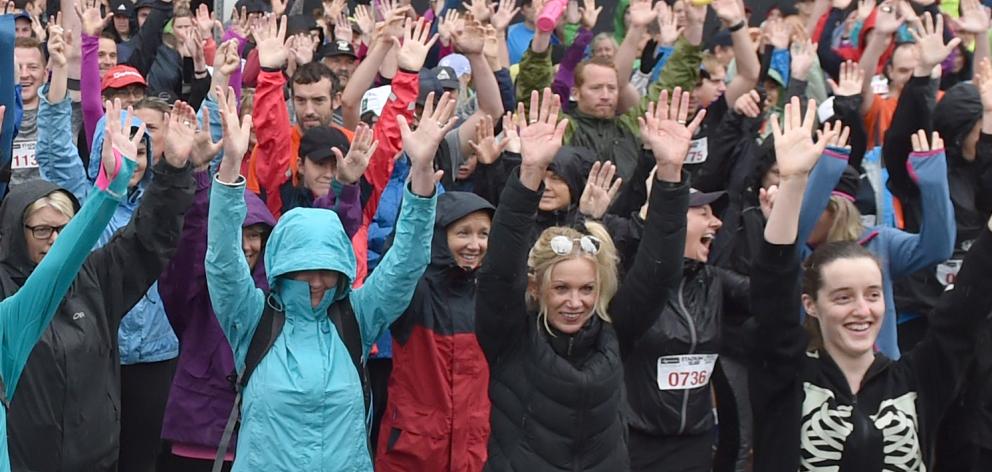 Participants warm up before running and walking in the wet for this year's Stadium to Surf fun run. Photo: Peter McIntosh