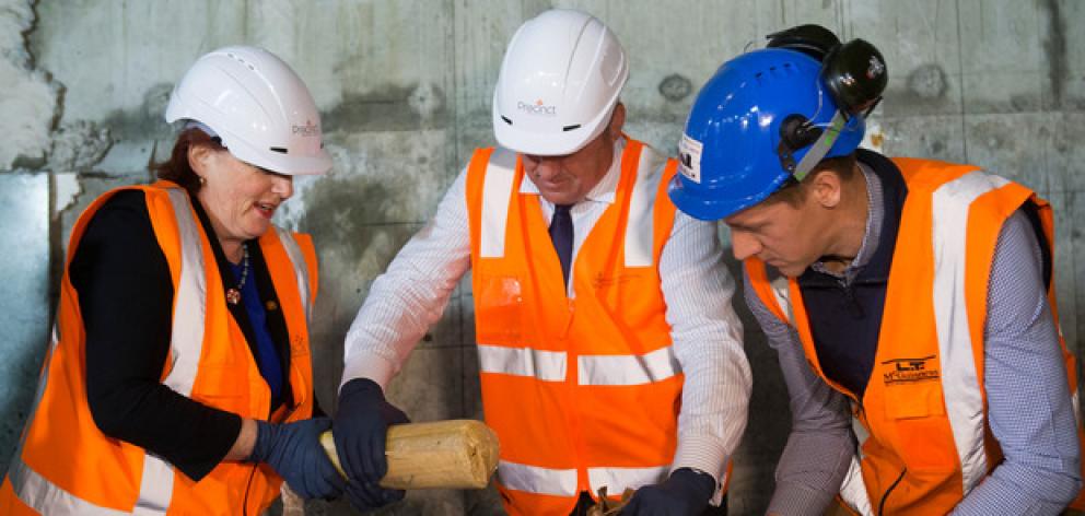 Maggie Barry, with help from Heritage NZ chief executive Andrew Coleman (centre) and contractor Russell Molder, manages to prise the contents from the time capsule. Photo: NZ Herald