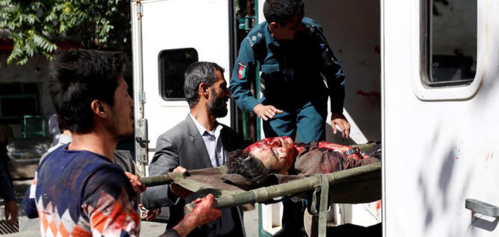 Men move an injured man to a hospital after a blast in Kabul, Afghanistan. Photo: Reuters