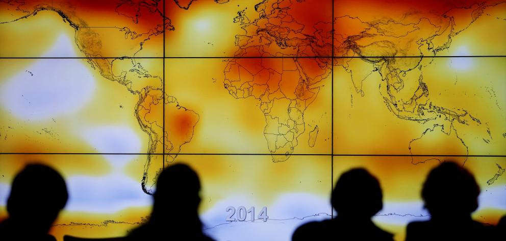 Participants look at a screen showing a world map with climate anomalies during a World Climate...