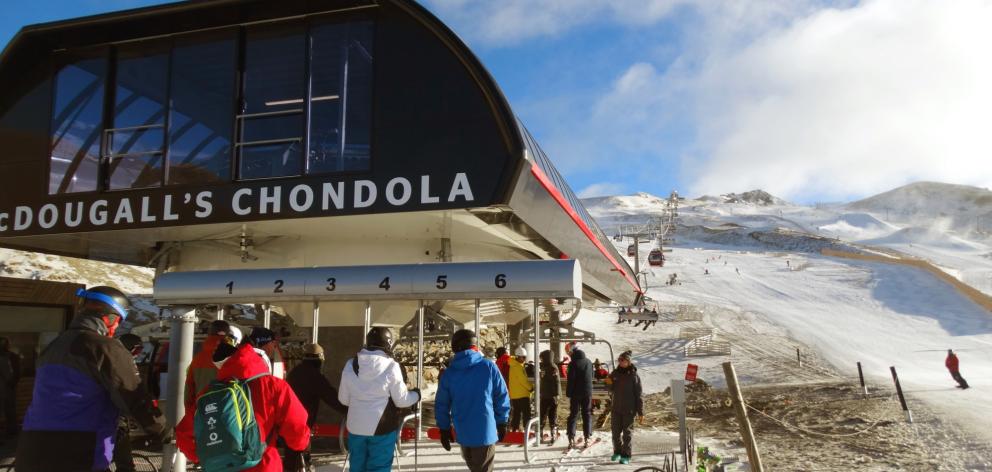 Skiers and snowboarders queue at the base of the new McDougall’s Chondola ski lift on opening day...