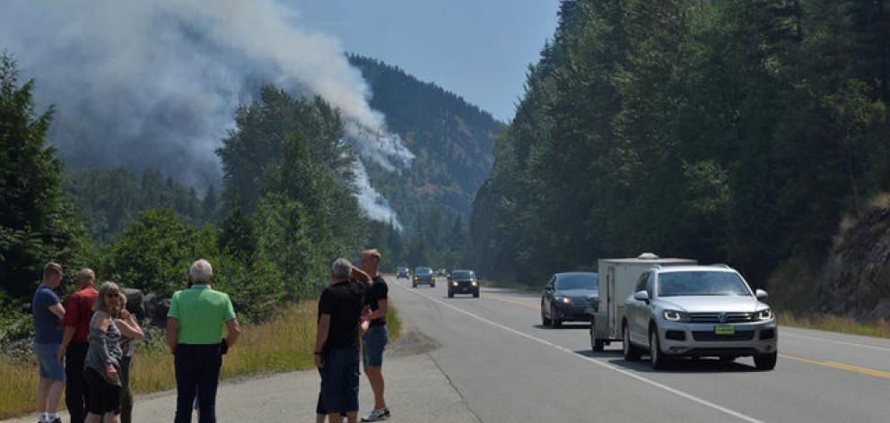 Tourists from Denmark stop to photograph one of several wildfires burning near Little Fort,...