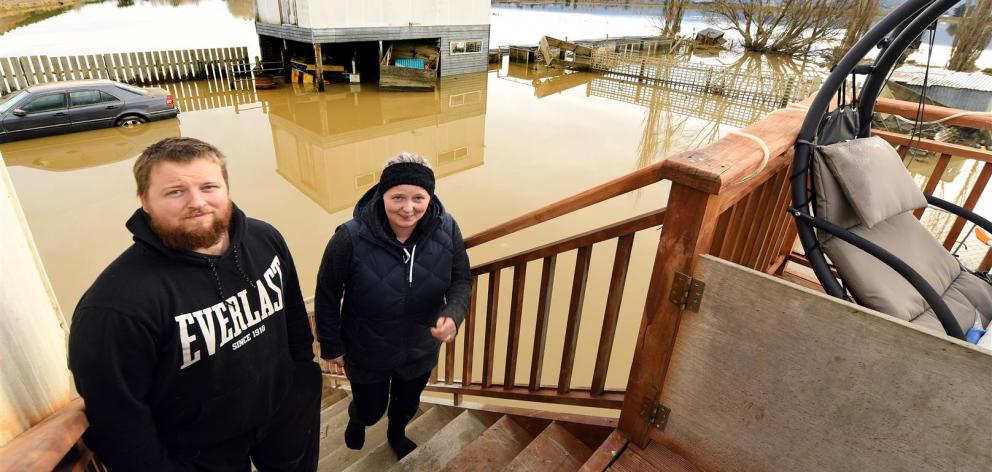 Henley residents Hamish and Emma McGregor stand clear of the floodwater which has inundated their backyard. Photo: Stephen Jaquiery