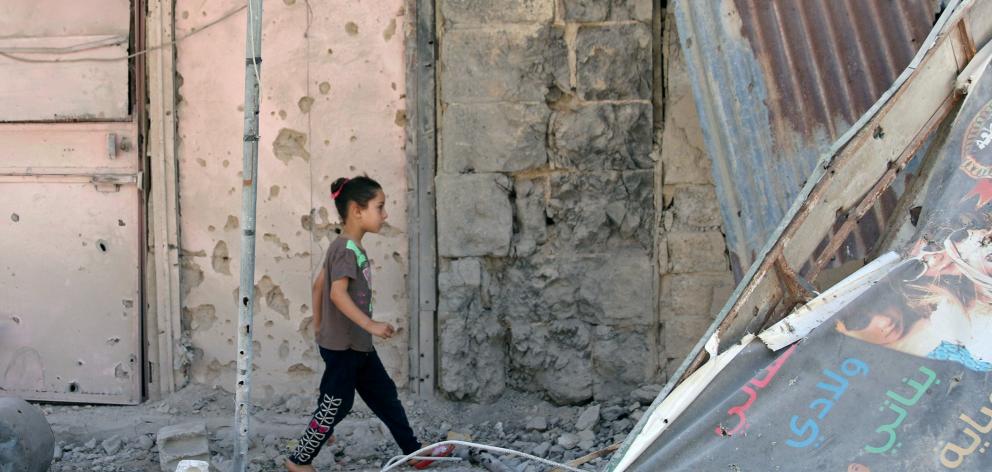 A girl walks on debris in a rebel-held part of the southern city of Deraa, Syria. Photo: Reuters
