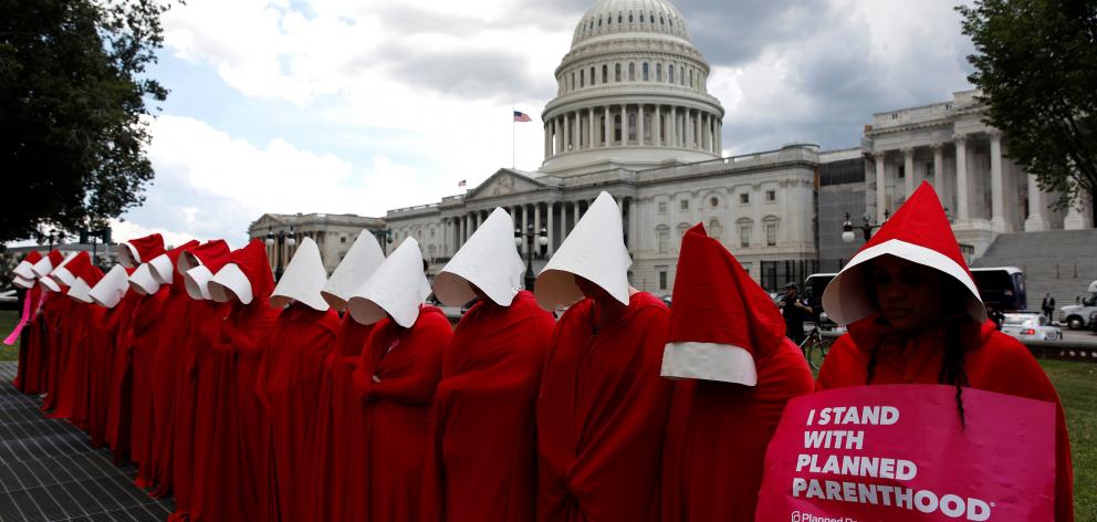 Women dressed as handmaids from the novel, film and television series The Handmaid’s Tale...