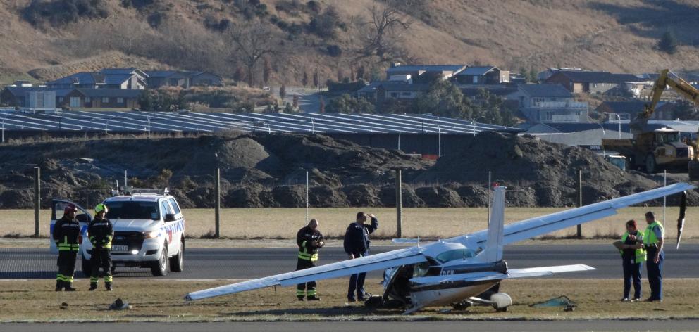 Police and Queenstown Airport fire rescue staff examine a Cessna 177 that crashed just after take-off at the airport yesterday. Photo: Guy Williams