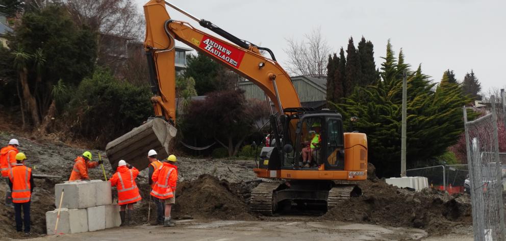 Workers remove debris blocking Lakeside Rd and install concrete blocks at the road edge. Photo:...