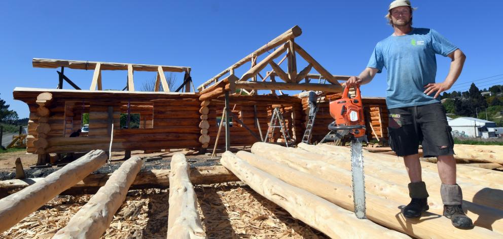 Mat Rusher with the log cabin he has built, and is about to deconstruct. Photo: Stephen Jaquiery