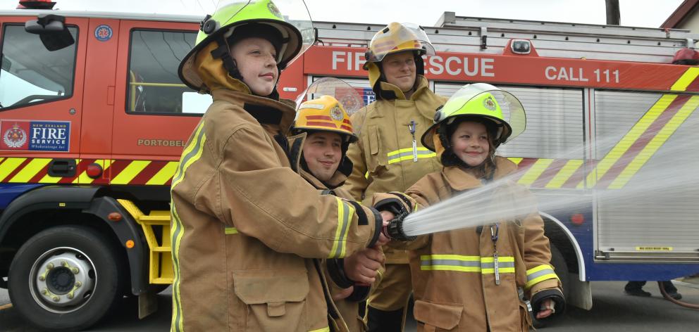  Charitable youngsters Taylor McLean, second from left, and her sister Kate try using a fire hose...