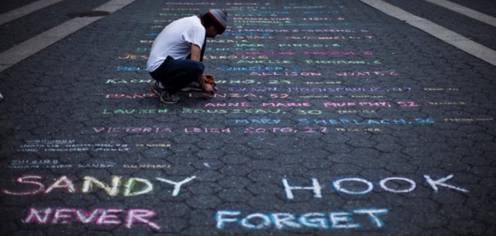 Street artist Panzarino prepares a memorial as he writes the names of the Sandy Hook Elementary School victims. Photo: Reuters