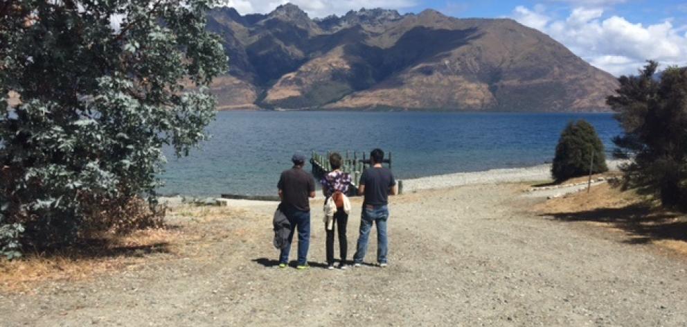 The parents and brother of missing American man Tyler Nii look across Lake Wakatipu from the...