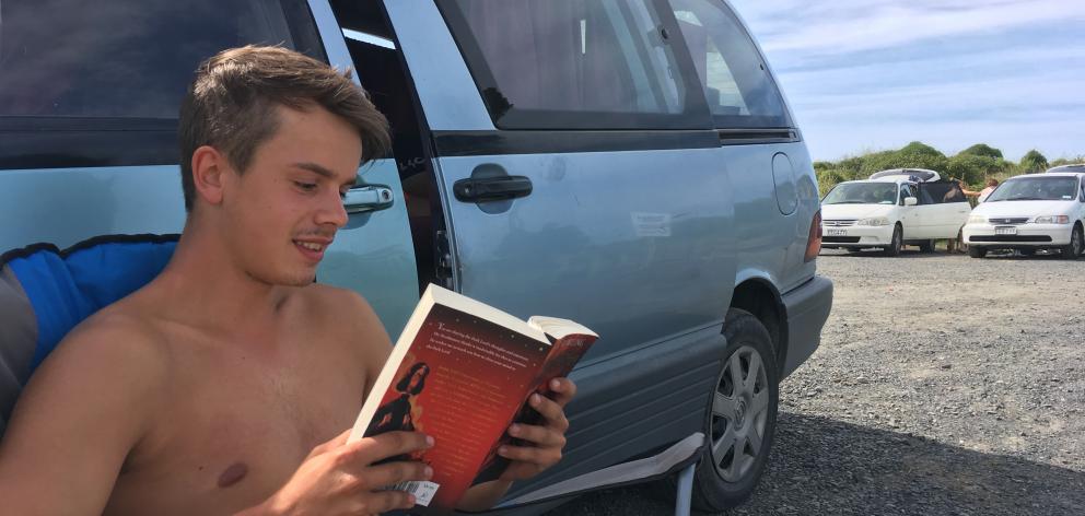 German freedom camper Paul Drabek, of Stuttgart, reads a Harry Potter book in the car park at Ocean View Recreation Reserve last week. PHOTO: SHAWN MCAVINUE