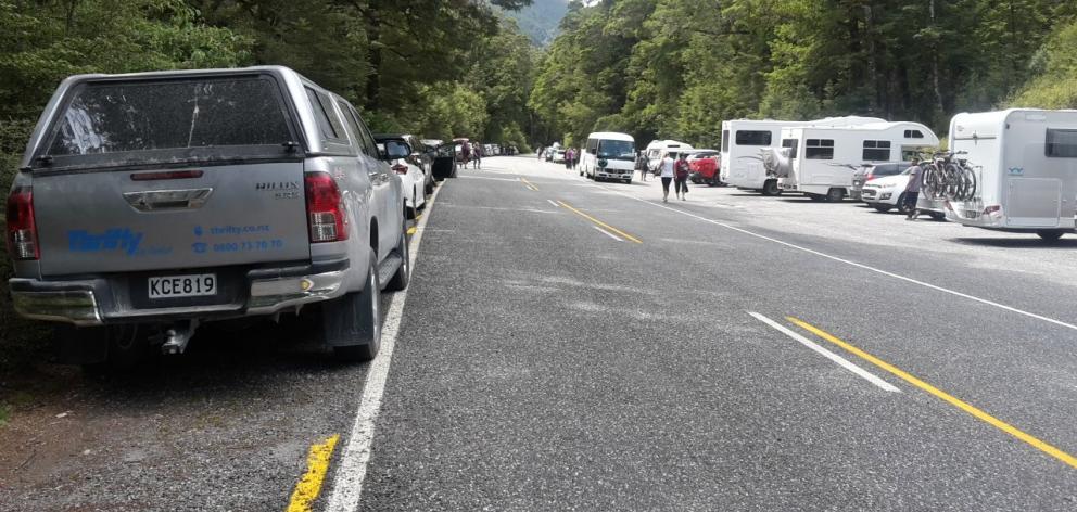 Cars and camper vans are parked beside State Highway 6 near Makarora while their occupants visit...