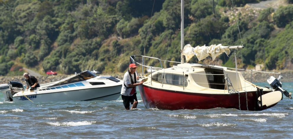Brent Young (left, in power boat) prepares to tow a stricken yacht off a mud-bed near the entrance to the Otago Yacht Club where it drifted after its motor broke down yesterday. The yachtsman (right), who only wanted to be known as John, was pleased when
