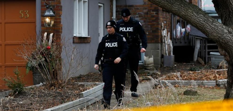 Police officers guard the grounds of a house they had searched in Toronto. Photo: Reuters