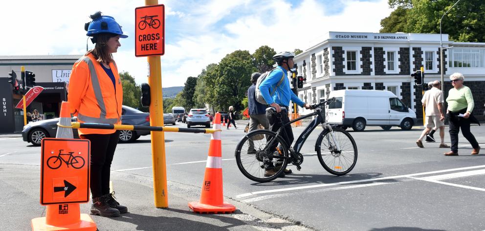 Under the watchful eye of Lydia Perkins, of Fulton Hogan, NZ Transport Agency project manager Simon Underwood wheels his e-bike across Great King St to reach the revamped section of cycleway. Photo: Peter McIntosh