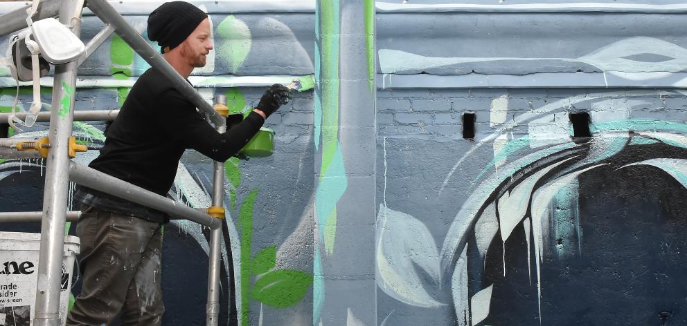 Street artist Ian Ross works on a wall at Heritage Coffee in Vogel St yesterday. Photo: Gregor Richardson