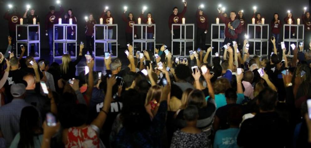 Local students, including some from Marjory Stoneman Douglas High School, hold up their phone lights at the end of a vigil for victims of the school shooting. Photo: Reuters