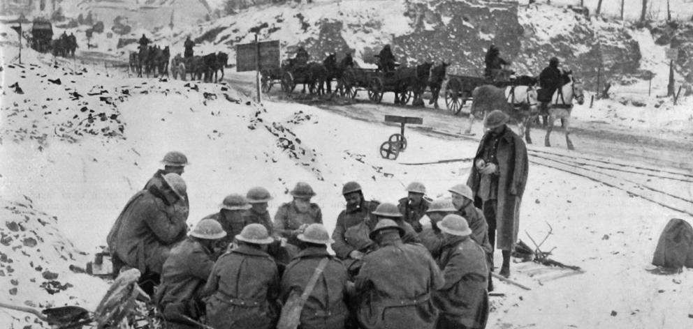 A scene on the British Western Front: troops warming themselves around a fire by the roadside. —...