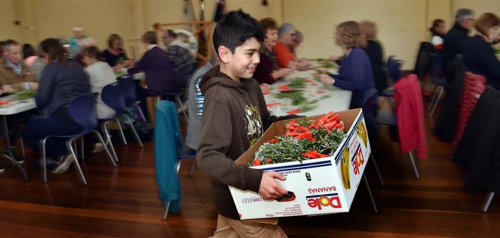 Cobie Smith (9) gathers the posies created in the HMNZS Toroa Dunedin naval reserve headquarters...