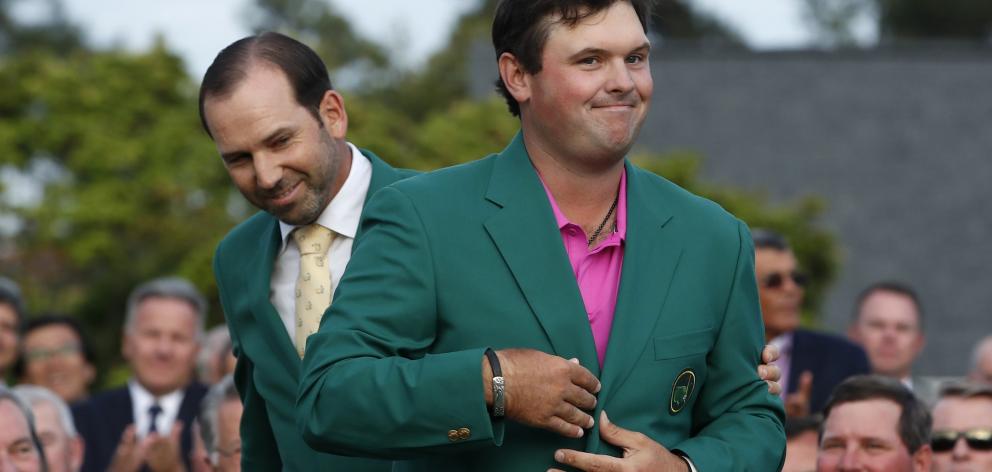 Sergio Garcia of Spain (rear) looks on after helping put the green jacket on 2018 Masters winner...