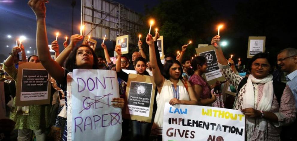 People hold candles and placards during a protest against the rape of an eight-year-old girl and an eleven-year-old girl in India. Photo: Reuters