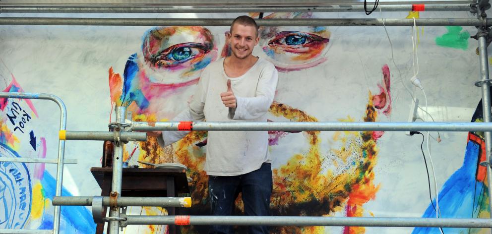 Artist Tyler Kennedy Stent stands between the eyes of Ed Sheeran, a controversial mural he was...