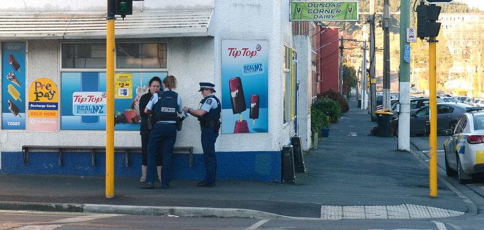Police talk to a woman outside the Dundas Corner Dairy in North Dunedin yesterday afternoon...