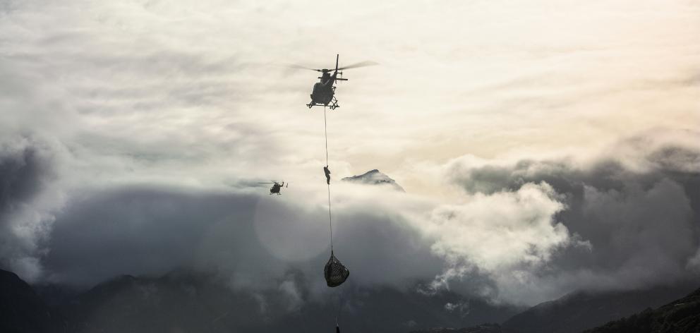 Tom Cruise climbs a rope towards a helicopter as part of a stunt in Mission:  Impossible —...