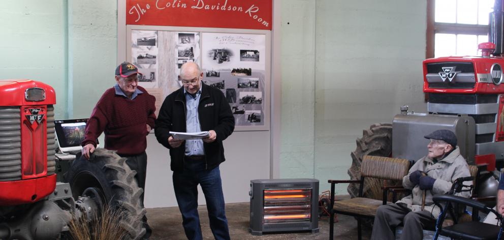 Lenny Balneaves (centre), of JJ Ltd, reads an account of the exploits of Colin Davidson (left) and Jack Johnstone (right) at the unveiling of a plaque naming the Central Southland Vintage Machinery Club's room near Winton after Mr Davidson. Photo: Nicole 