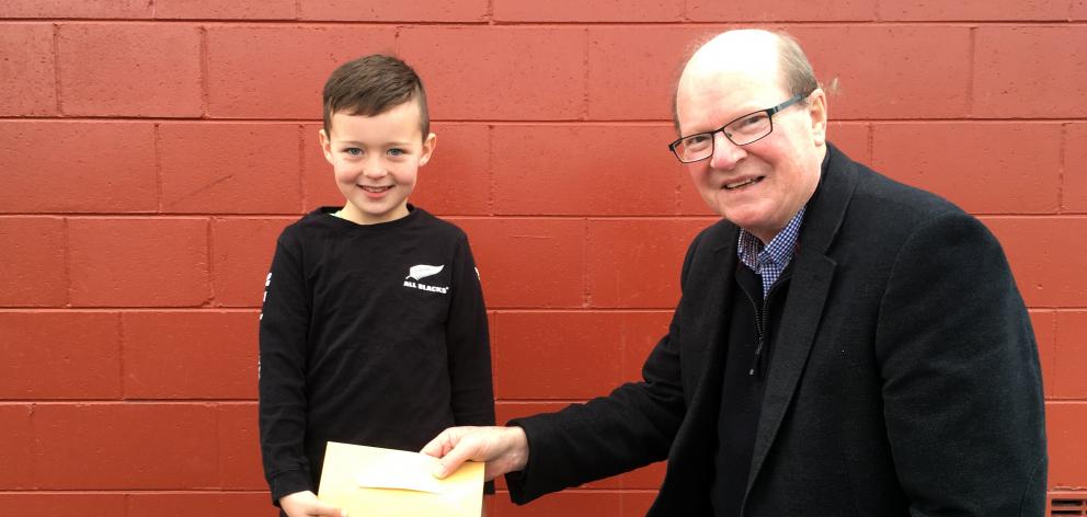 Mason Dunphy gives Taieri Facilities Community Trust member Bill Feather $280 on Tuesday to help build a new aquatic facility in Mosgiel. Photo: Shawn McAvinue