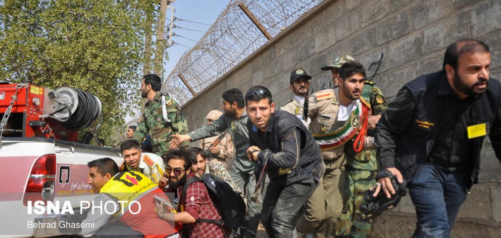 Reporters and military personal take shelter behind a truck during the attack on a military...