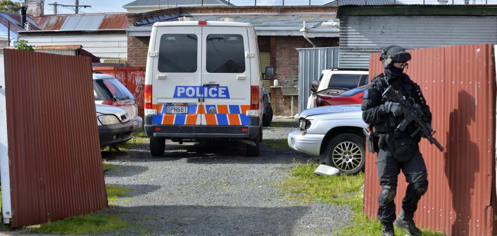 A member of the armed offenders squad stands guard outside a yard in Bathgate St which, alongside...