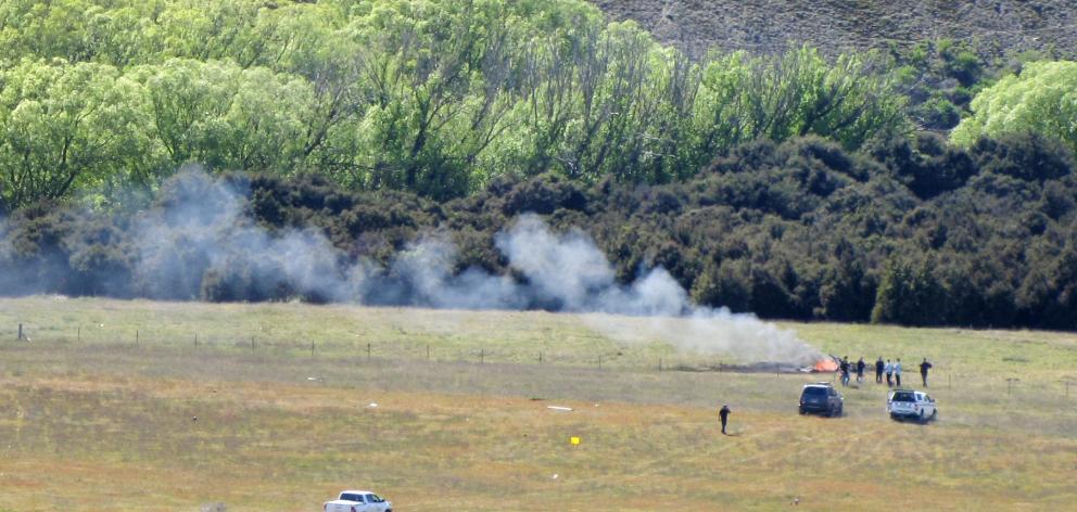 Smoke rises from the wreck of a helicopter crash near Wanaka Airport earlier today. Photo: Mark Price