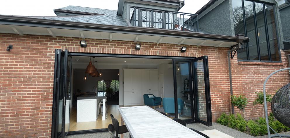 Large bifold doors open the kitchen-family area to a patio designed by Wayne Butson of Design and...
