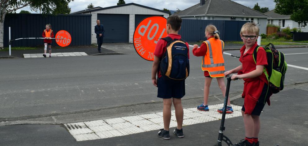 Silverstream School pupil Luke McHale (8) prepares to cross Green St in Mosgiel on his scooter with pupil Beau French (11) under the guidance of pupils and road patrollers Sarah Evans (left), Hannah Bray (both 10) and principal Greg Hurley. Photo: Shawn M