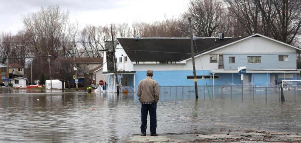 A man looks out at a flooded residential area in Gatineau, Quebec, Canada. Photo: Reuters A man looks out at a flooded residential area in Gatineau, Quebec, Canada. Photo: Reuters
