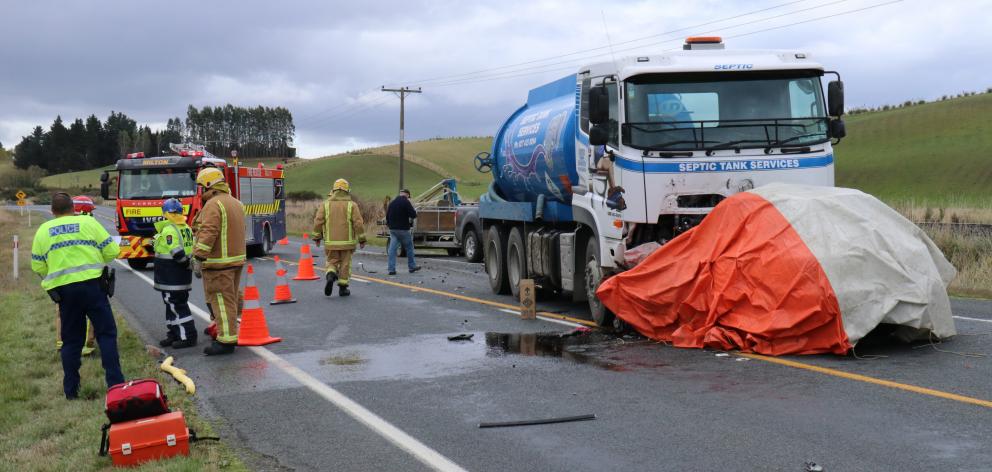 Emergency services work at the scene of a crash between a septic tank truck and a car near...