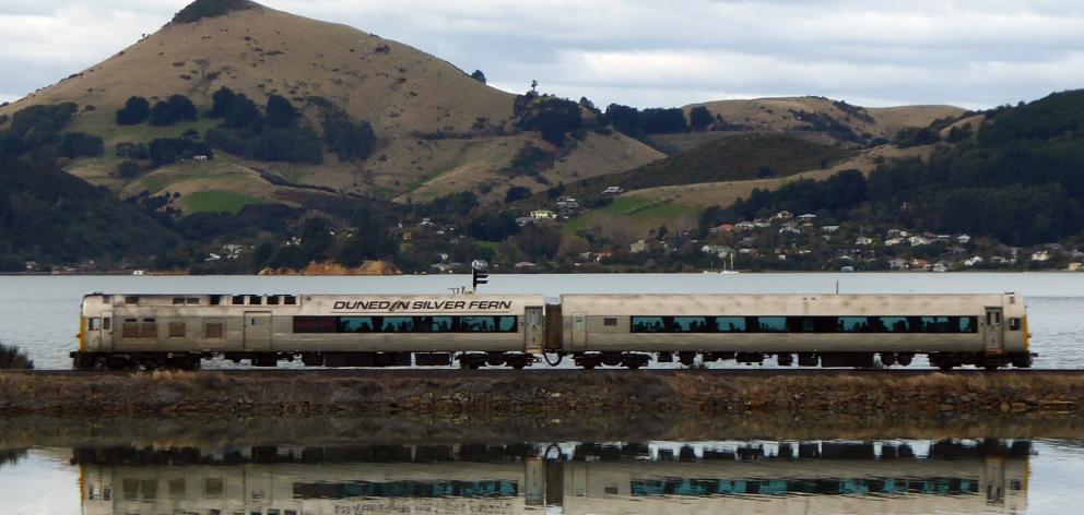 Dunedin's Silver Fern rail car crosses the causeway at Blanket Bay, with Otago Peninsula's...