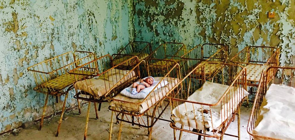 A rusting cot containing a baby doll and blanket sits in the Pripyat hospital maternity ward.