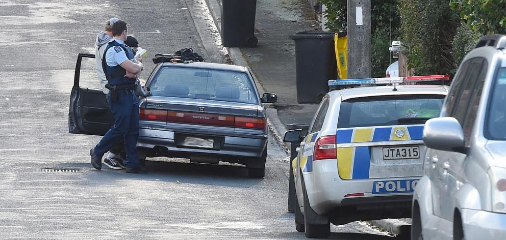 Police search a car parked in Craigleith St yesterday afternoon after reports of a group of men...