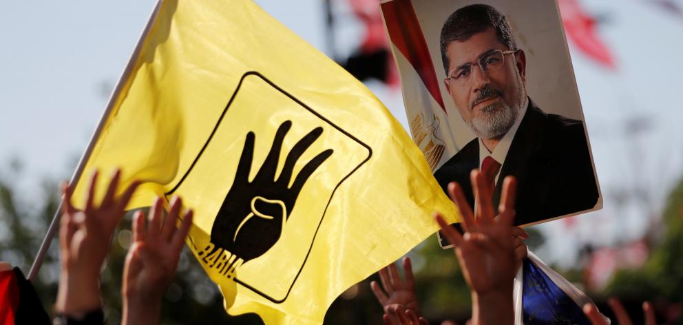 NO ARCHIVEPeople flash Rabia signs as they hold a picture of former Egyptian president Mursi during a symbolic funeral prayer in Istanbul. Photo: Reuters