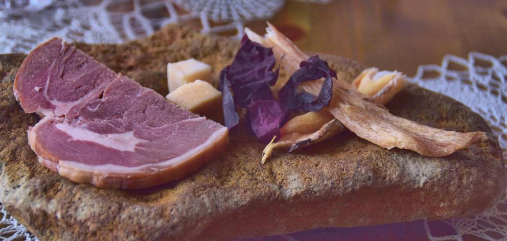 Entree of smoked lamb, dried cod and fermented shark. The yellow cubes are the shark. The serving...